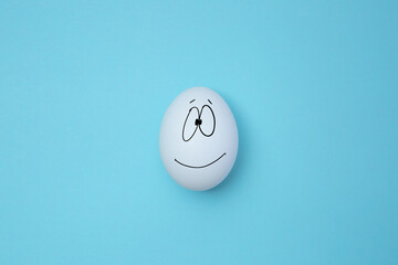 White egg smiling on the blue background. Copy space. Emoticons concept. Art collage
