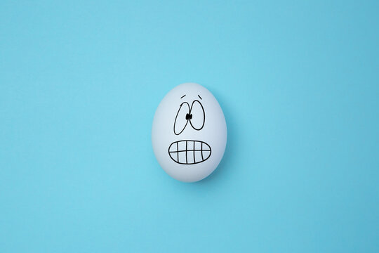 Funny egg emoji, isolated on blue background. Copy space. Emoticons concept. Art collage