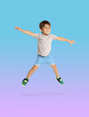 Fototapeta premium Happy boy jumping on color gradient background