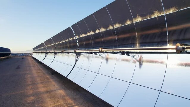 Solar thermal power plant at sunrise. Mirrors reflecting the sun, heating the water flowing through a metallic tube passing through a turbine that converts steam into electricity. Aerial video