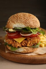 Delicious burger with crispy chicken patty on wooden table, closeup