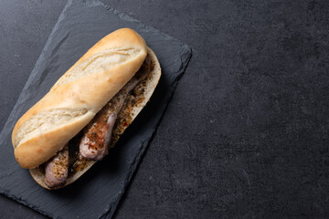 Traditional choripan, Argentina sandwich with chorizo and chimichurri sauce on black slate...