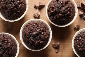 Delicious chocolate muffins on wooden table, flat lay