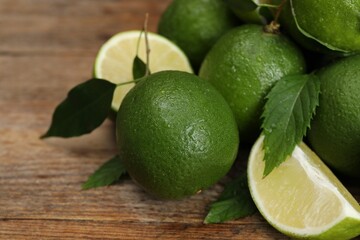Pile of fresh wet limes and leaves on wooden table, closeup