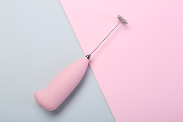 Pink milk frother wand on color background, top view
