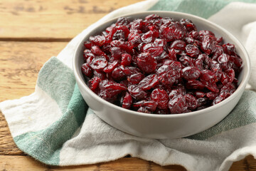 Tasty dried cranberries in bowl on wooden table, closeup