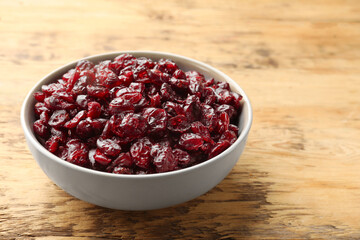 Tasty dried cranberries in bowl on wooden table, closeup