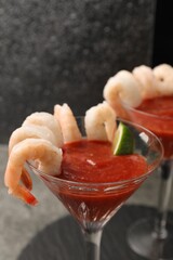 Tasty shrimp cocktail with sauce and lime in glasses on table, closeup