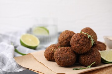 Delicious falafel balls, arugula and lime on table, closeup. Space for text