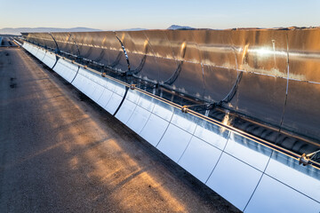 Solar thermal power plant at sunrise. Mirrors reflecting the sun, heating the water flowing through...