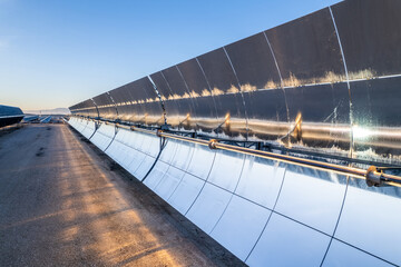 Solar thermal power plant at sunrise. Mirrors reflecting the sun, heating the water flowing through...