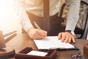Lawyer working with document at wooden table in office, closeup
