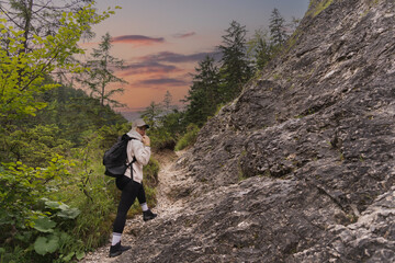 A girl with a briefcase behind her back is hiking in the spring in the Polish Tatra Mountains.