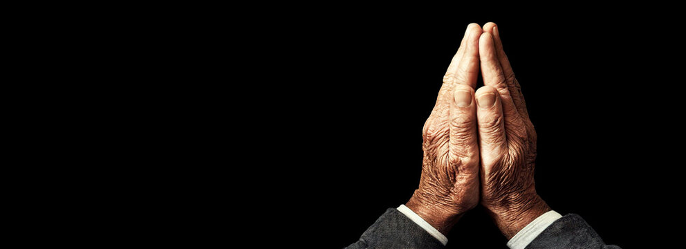 Closeup of hands clasped in prayer (wrinkled hands) of an elderly man, isolated on black background with copy space. Classical gesture of a person praying God in the Christian religion. Generative Ai.