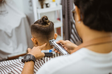 asian customer getting hair trimming in barbershop back view