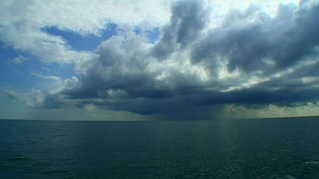 Seascape -the open sea, calm water surface, a large thundercloud in the sky.