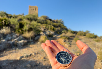 Compass in hand in mountains. Tourist compass for orientation on terrain. Magnetic declination...