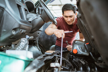 a male mechanic checks the engine under the car seat at a repair shop