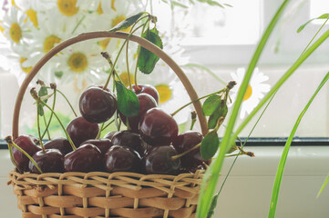 Small basket with cherries on a window with a blurred background. Selective focus, natural light