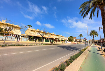 Bicycle path and pedestrian sidewalk near the road and roadway on the street near houses. Green bike and jogging path. Holiday home, house or holiday villa in Spain.