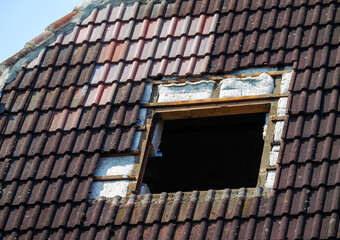 The afternoon sun casts shadows on the weathered tiles of an reparing building, highlighting the...