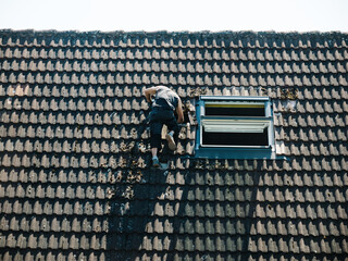 A unrecognizable worker repairing tiles on the roofing during the general inspection of the house...
