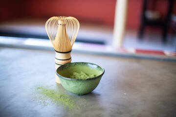 matcha powder beside a traditional bamboo whisk
