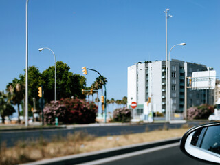 A unique tilt-shift lens capture of Av. de Gabriel Roca, featuring cars and an apartment building by the seaside in the background, seen from inside a moving car.