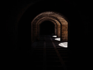 Discover the enchantment of a dark tunnel with a captivating beam of light at its end in Mallorca, Palma de Mallorca, Spain, surrounded by the magnificent architecture of Catedral-Baslica de Santa