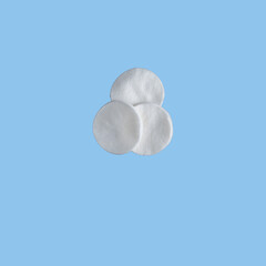 three isolated cotton pads for facial cleansing on blue background