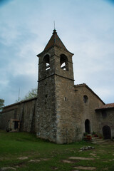 Fototapeta premium Sanctuary located on a plain above the Sierra de Cabrera, at 1,294 meters above sea level, Sanctuary of the Virgin of Cabrera. Vertical photograph at sunset on a very cloudy day. Osona Catalonia Spain