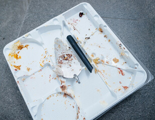 Intrigue unfolds as only a broken spatula rests on an empty plastic cake tray, amidst the remnants of an afterparty