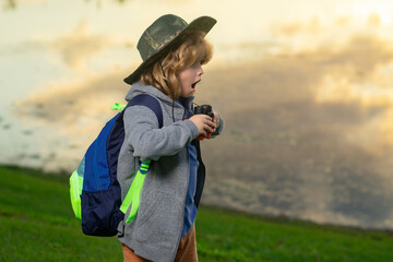 Traveler tourist kid. Happy child playing with binoculars. Explore and adventure. Child boy with backpacks exploring nature and environment. Outdoor leisure activity for children.