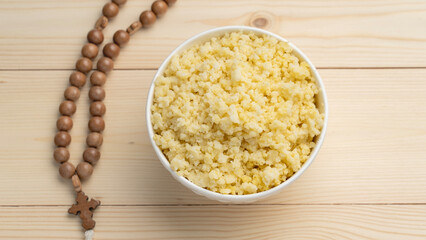 Millet porridge and prayer beads on a wooden table during the Great Christian Fast. Lenten food during the Great Orthodox Lent