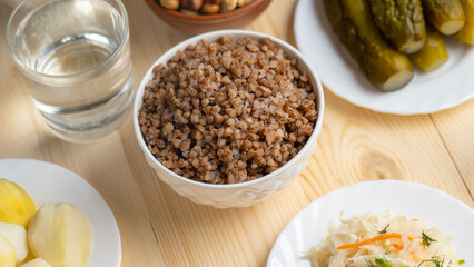 Buckwheat porridge, a glass of water, boiled potatoes and pickled cucumbers on a wooden table, Lenten food during the Great Orthodox Lent