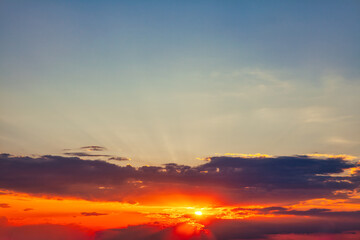 Sunset sky background with clouds and sun rays. Beautiful nature scene in the evening