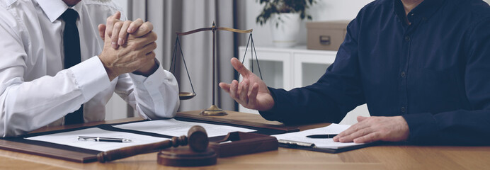 Lawyer working with client at wooden table in office, closeup. Banner design