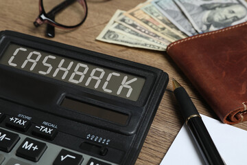 Calculator with word Cashback, pen, wallet and money on wooden table, closeup