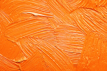 Strokes of orange oil paint as background, closeup