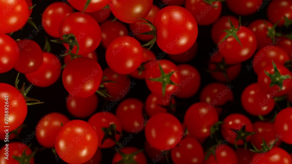 Poster super slow motion of cherry tomatoes flying on black background. filmed on high speed cinema camera,