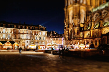 Majestic Place de Chateau with illuminated Notre-Dame de Strasbourg Cathedral at dusk during Christmas Market with pedestrians discovering the place