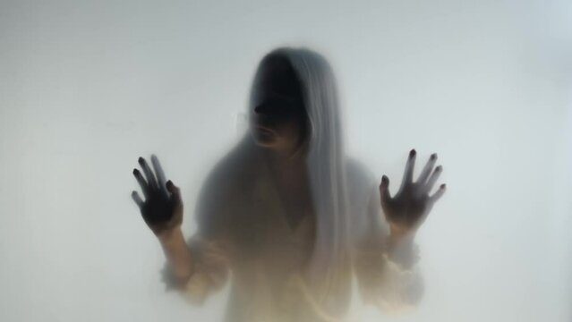 Silhouette of a woman behind a frosted glass or curtain in the fog. The ghostly woman touches the stele with her face and hands.