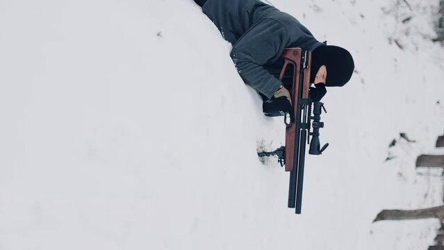  a man with a rifle on the snow and aims at a target