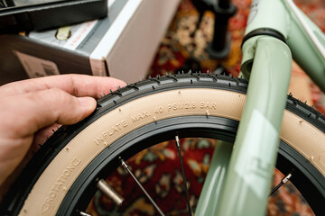 A detailed view of a persons hand on a bicycle tire, highlighting the embossed technical specifications and maximum inflation pressure.