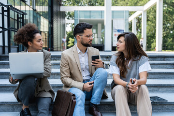 Group of young business people, job candidates standing in front of the office building waiting to be called to meeting with the employer. Businessmen and businesswomen waiting for human resources