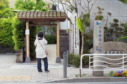 TOKYO, JAPAN - April 20, 2019: A visitor taking a photo in front of an entrance to Basho Memorial Hall, a museum in Koto Ward about the Japanese haiku poet Matsuo Basho.