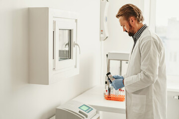 Scientist in uniform holding test tubes at laboratory. Medicine and research in chemistry