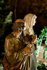An intricately detailed statue of Joseph and Mary, highlighted by artificial lighting, captures a serene biblical scene against the backdrop of the night.