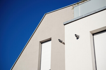 Modern building facade with clean lines, contrasting against a clear blue sky, featuring gas boile chimneys and closed shutters