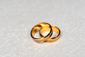 Obraz na płótnie Canvas wedding rings. two golden wedding rings lie on a white shiny table, viewed from afar, wedding concept